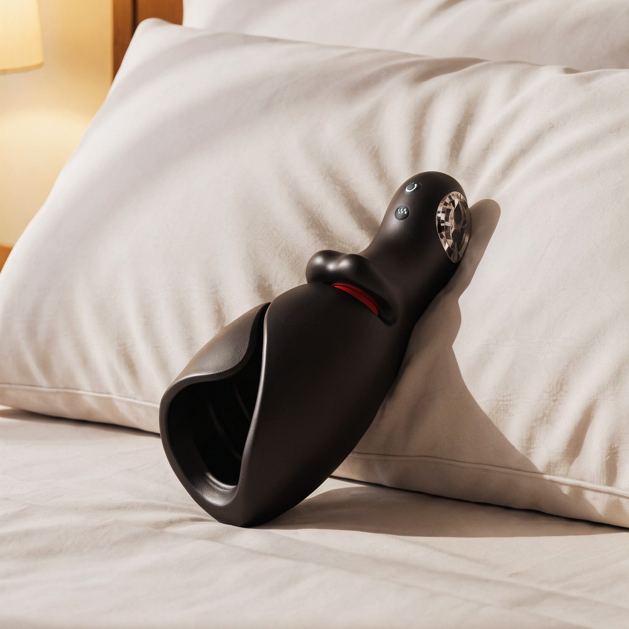 Black massage device on a bed with pillows in the background