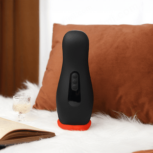 Black and red electronic device on a white surface with brown pillows in the background